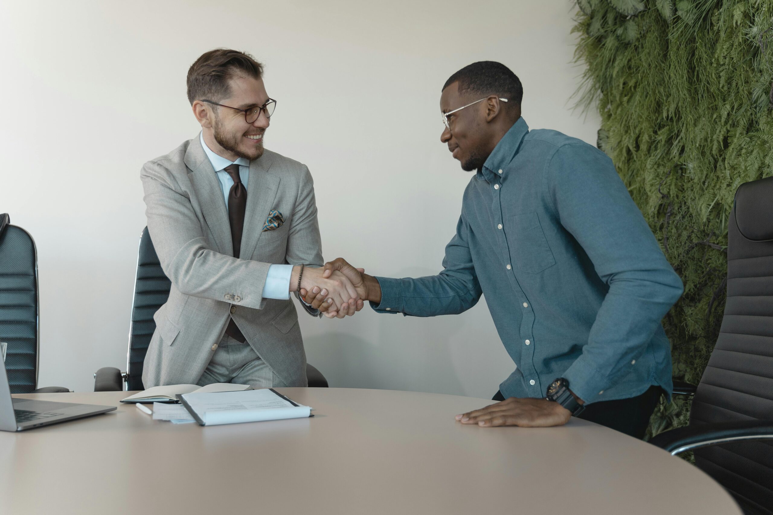 Two men shaking hands during a professional business meeting in a modern office.