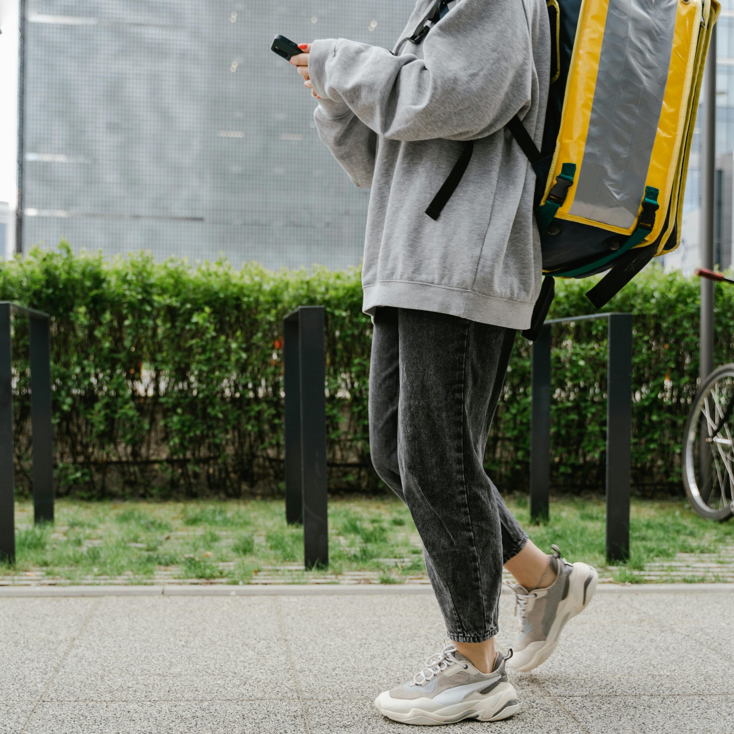 Delivery person walking with a thermal backpack in an urban setting, representing modern courier services.